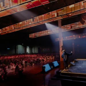 Auditorio de la Bitcoin Conference 2025 con asistentes y escenario iluminado en tonos azules