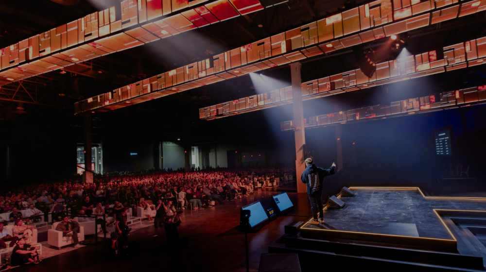 Auditorio de la Bitcoin Conference 2025 con asistentes y escenario iluminado en tonos azules