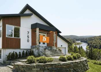 Una vivienda sobre una colina con una bandera naranja con el logo de Bitcoin.