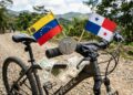 Moneda física de USDT sobre una bicicleta, con la bandera de Venezuela y Panamá, y dólares alrededor.