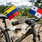 Moneda física de USDT sobre una bicicleta, con la bandera de Venezuela y Panamá, y dólares alrededor.