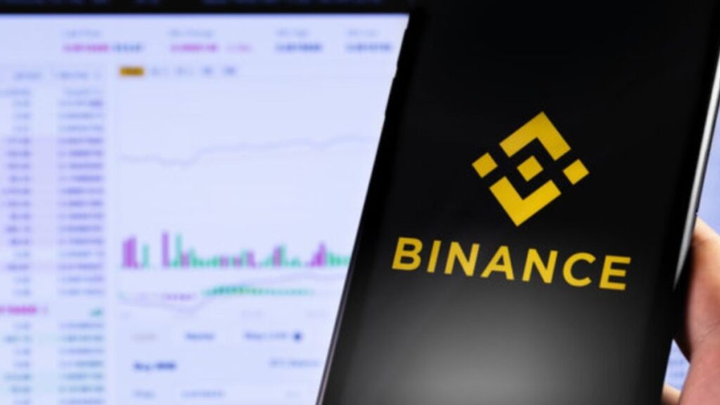 Mano sujetando un teléfono inteligente que muestra el logo de Binance.
