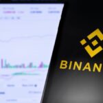 Mano sujetando un teléfono inteligente que muestra el logo de Binance.