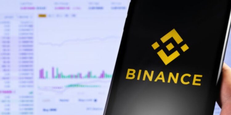 Mano sujetando un teléfono inteligente que muestra el logo de Binance.