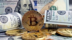 Moneda física de bitcoin dorada rodeada de billetes de 100 dólares estadounidenses.