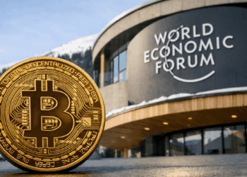 Moneda física de bitcoin delante del edificio del Foro Económico Mundial.