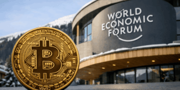 Moneda física de bitcoin delante del edificio del Foro Económico Mundial.