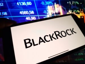 Un celular que muestra el logo de BlackRock delante de una pantalla de precios.
