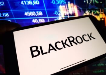 Un celular que muestra el logo de BlackRock delante de una pantalla de precios.