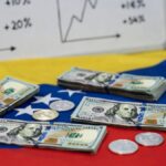 Dólares en una mesa con la bandera de Venezuela, con algunas monedas de USDT, y un pizarrón de gráficas alcistas.