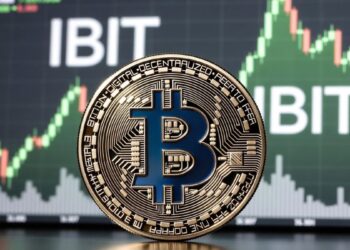 Una moneda física de bitcoin dorada y al fondo aparece una pantalla de trading con un gráfico alcista en tonos verdes.