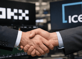 En primer plano, un apretón de manos. En el fondo, los logos de OKX e ICE.