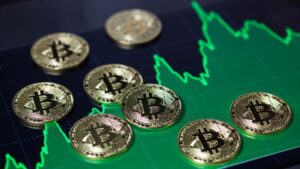 Monedas físicas de bitcoin sobre un gráfico de precios alcista.
