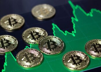 Monedas físicas de bitcoin sobre un gráfico de precios alcista.