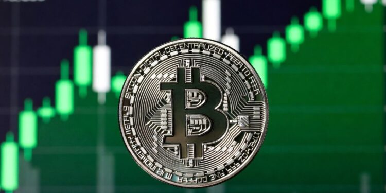 Moneda física de bitcoin en primer plano con un fondo de gráfico alcista en verde.