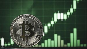 Moneda física de bitcoin en primer plano y gráfico de velas verdes alcista de fondo, representando subida de precio.