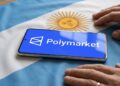 Teléfono inteligente que muestra el logo de Polymarket sobre una bandera de Argentina y con dos manos al lado.
