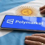 Telรฉfono inteligente que muestra el logo de Polymarket sobre una bandera de Argentina y con dos manos al lado.