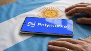 Teléfono inteligente que muestra el logo de Polymarket sobre una bandera de Argentina y con dos manos al lado.