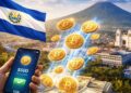 Teléfono inteligente tomado por una mano, enviando bitcoin a una ciudad de El Salvador, con la bandera del país y un volcán en el fondo.