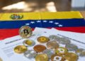 Monedas físicas de bitcoin y criptomonedas, con la bandera de Venezuela y papeles que dicen DECLARACIÓN DE CRIPTOMONEDAS.
