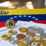 Monedas físicas de bitcoin y criptomonedas, con la bandera de Venezuela y papeles que dicen DECLARACIÓN DE CRIPTOMONEDAS.