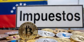 Monedas físicas de bitcoin y criptomonedas, junto a la bandera de Venezuela y un cartel que dice "Impuestos".