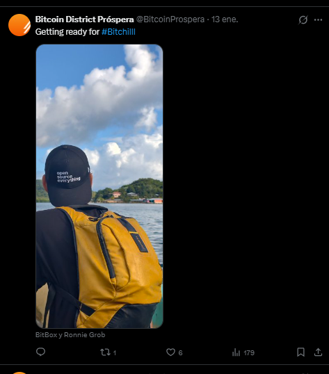 Una persona de espaldas mirando hacia el horizonte, porta una mochila amarilla y una gorra en la que se lee la frase "open source everything".