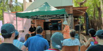 Un grupo de personas están de espaldas observando la exposición de un ponente en el evento Bitcoin Freedom de Costa Rica.
