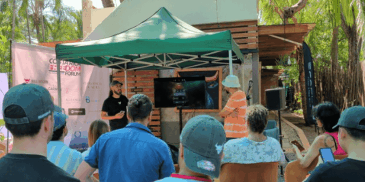 Un grupo de personas están de espaldas observando la exposición de un ponente en el evento Bitcoin Freedom de Costa Rica.