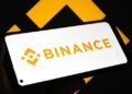 Logo de Binance atrás con el logo de Binance en un teléfono inteligente