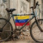 Una bicicleta en mal estado que tiene el logo de USDT, dólares y la bandera de Venezuela.
