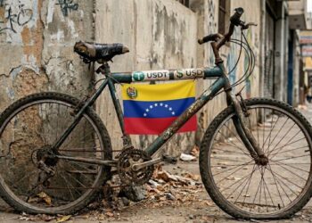 Una bicicleta en mal estado que tiene el logo de USDT, dólares y la bandera de Venezuela.