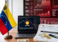 Bandera de Venezuela, junto a bitcoin y criptomonedas, y papeles que dicen "recaudación fiscal", con gráficas rojas en el fondo.