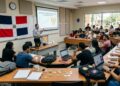 Salón de clases con universitarios, bitcoin alrededor y la bandera de República Dominicana.