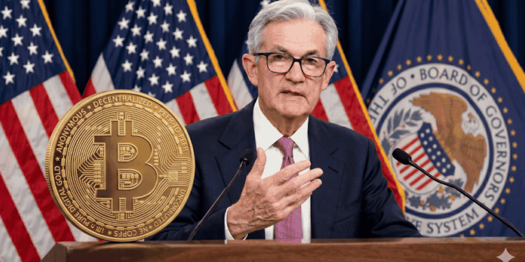 Jerome Powell hablando en un discurso, con una moneda física de bitcoin sobre su atril.