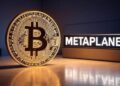 Moneda física de bitcoin junto a un letrero de Metaplanet.