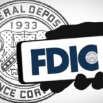 Mano humana sosteniendo un telรฉfono inteligente que refleja el logo de la FDIC y de fondo el sello de esa instituciรณn.