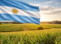 Una bandera argentina junto a tierras agrรญcolas.