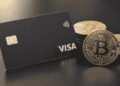 Imagen de una tarjeta VISA con unas monedas de bitcoin.
