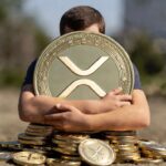 Una persona abraza una moneda física de XRP