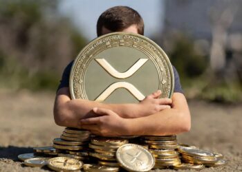 Una persona abraza una moneda física de XRP