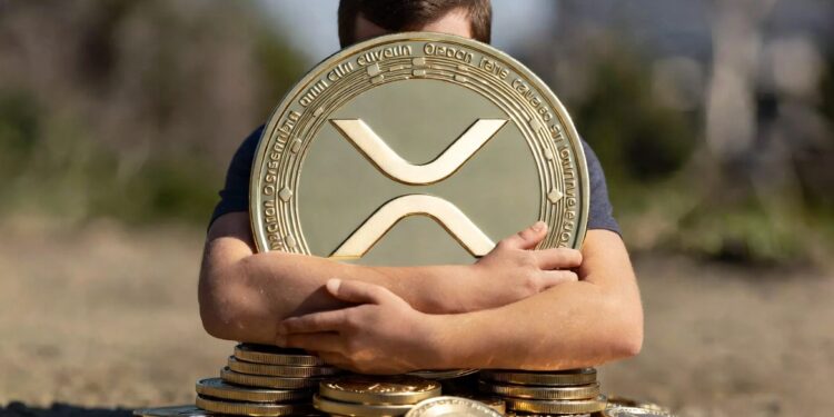 Una persona abraza una moneda física de XRP