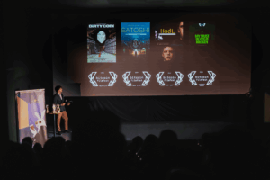 Sala de cine oscura con público viendo una pantalla que muestra pósteres del Bitcoin Film Fest.
