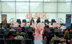 Conferencia sobre "Black Blockchain" con panelistas en el escenario y audiencia en formato horizontal.