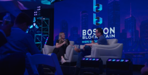 Imagen de un panel en vivo durante la Boston Blockchain Week con dos panelistas en el escenario.