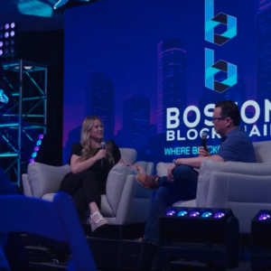 Imagen de un panel en vivo durante la Boston Blockchain Week con dos panelistas en el escenario.