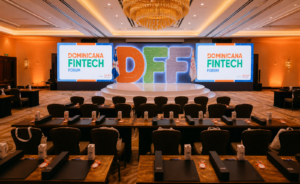 Sala de conferencia del Dominicana Fintech Forum con escenario iluminado, letras DFF y ambiente corporativo cálido.