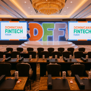 Sala de conferencia del Dominicana Fintech Forum con escenario iluminado, letras DFF y ambiente corporativo cálido.