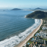 Vista panorámica aérea de Florianópolis, Brasil, mostrando el perfil costero de la ciudad bajo una luz cálida al atardecer.